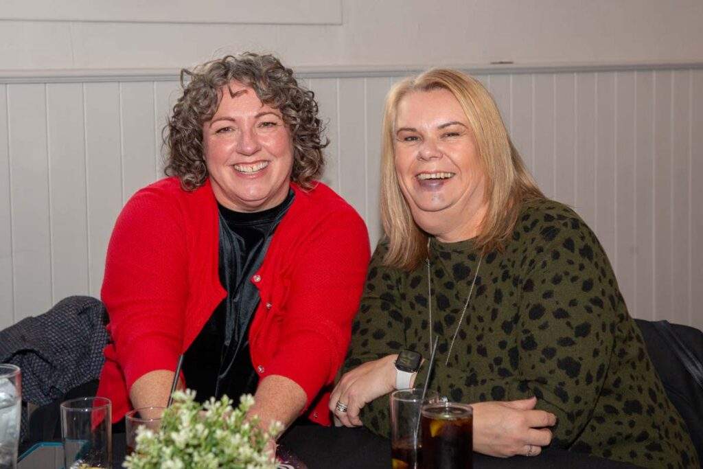 Two women smiling together at their table during Sight Life's afternoon tea event, enjoying the relaxed and friendly atmosphere.