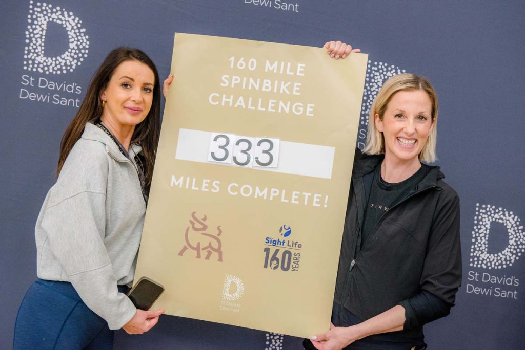 Picture of Eve from St David's Centre and Alex from Studio Tarw holding up the final total board showing 333 miles cycled.