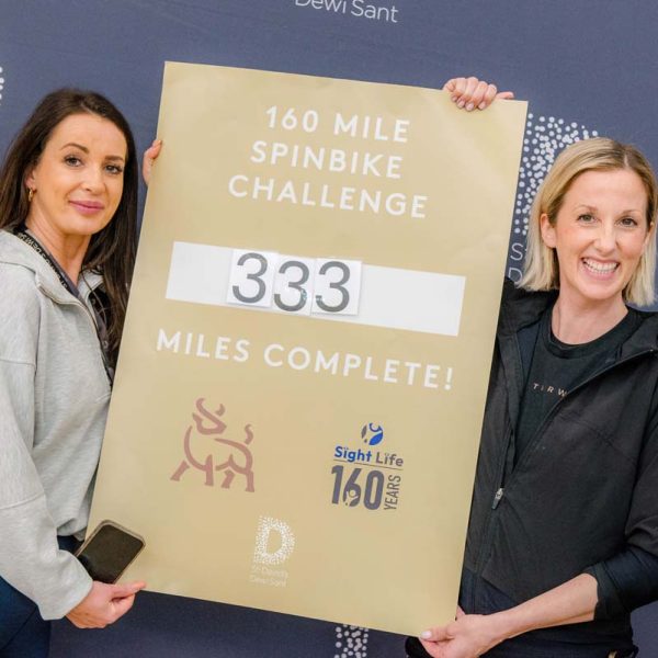 Picture of Eve from St David's Centre and Alex from Studio Tarw holding up the final total board showing 333 miles cycled.