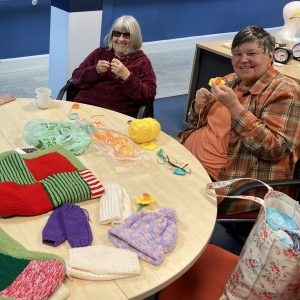 Some ladies at the knit and natter group sitting behind a table full of knitted items