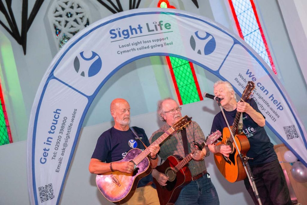 A close up angled shot of the three guitarists playing and singing on stage.