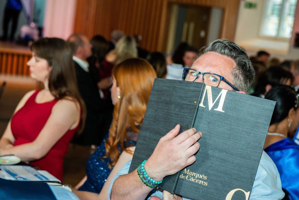 Steve Western sat at the table, peeking out from behind a drinks menu